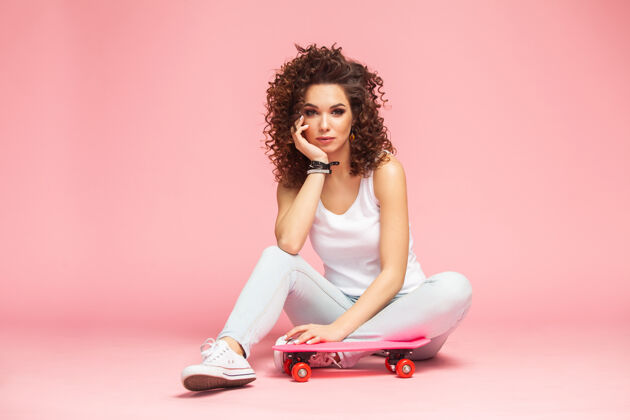 衣服快乐迷人的年轻女子坐在粉红色的滑板上人运动欢乐