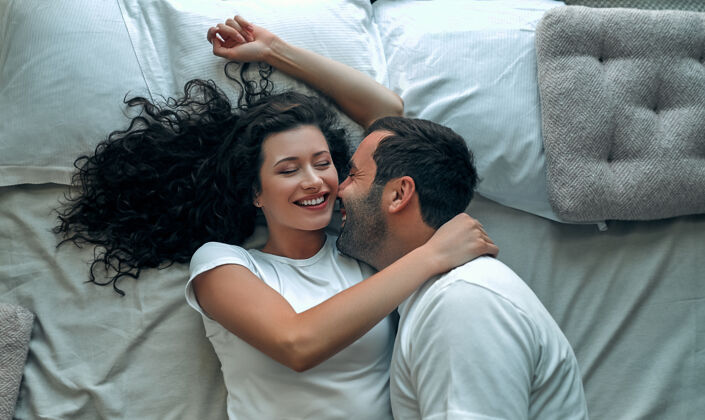 在一起美丽的情侣在床上接吻房间丈夫微笑