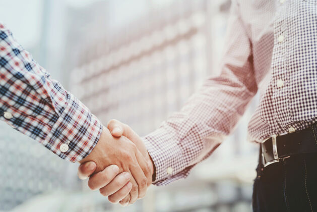 城市两人握手的特写镜头同事或谈判协议成功的工作男性男人白人