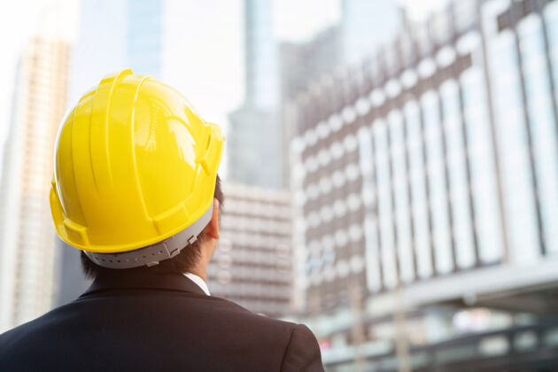 工人工程人员的后视图施工人员穿工作服为工作安全戴安全帽运行工程师立像工程成功经理项目现场男性建筑项目