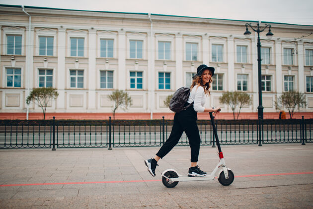 街道在城里骑着电动滑板车的年轻女子休闲电池速度