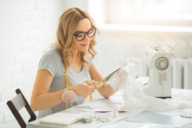 布料一个漂亮的年轻女人在工厂里 桌上摆着一台缝纫机职业工艺肖像