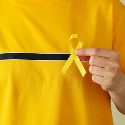 手穿黄色t恤的女士手持儿童癌症意识丝带孩子骨头疾病