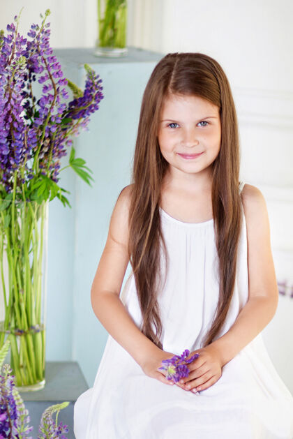 夏天美丽动情的小女孩坐在紫罗兰花丛中室内的花饰欢呼装饰花