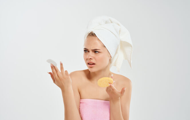 青少年头上戴着毛巾的女人手里拿着一块海绵美容皮肤模型斑点预防问题