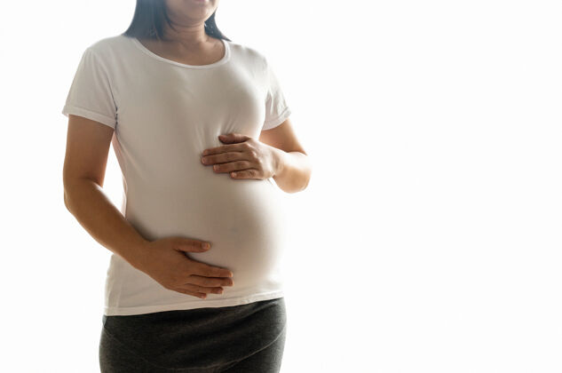 怀孕快乐的孕妇怀着宝宝在怀孕的肚子里隔离在白色的背景上保健妈妈怀孕