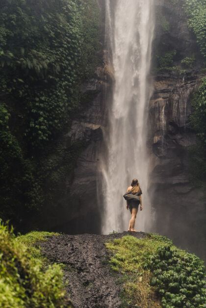 森林女孩站在一个巨大的瀑布前人目的地异国情调