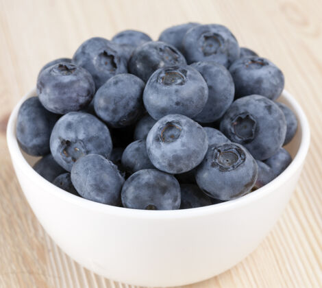 食物新鲜的大蓝莓放在一个白色的盘子里 放在一张浅色的桌子上 浆果的特写镜头很有用大自制甜点