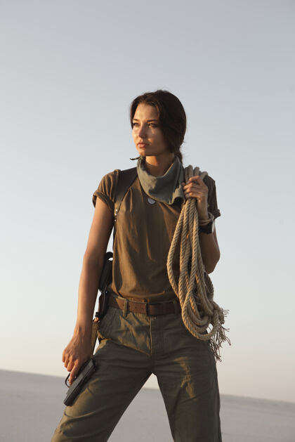 超级英雄站在户外的一个女人 手里拿着枪和绳子沙漠年轻凶残危险的持枪女孩战士高加索表情