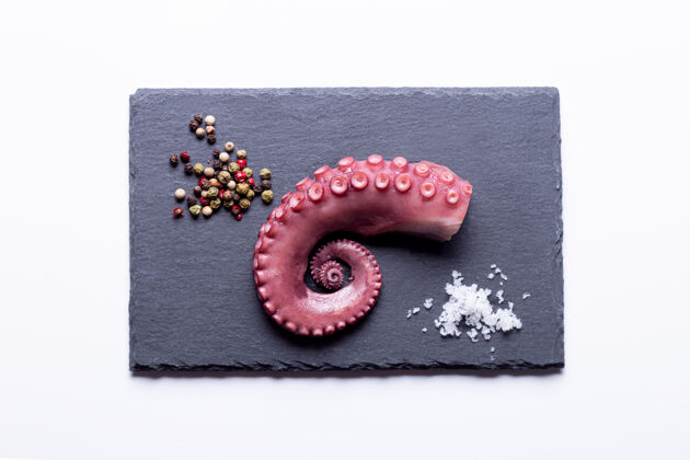 开胃菜在白色背景的石板上炖章鱼触须顶视图章鱼海鲜胡椒