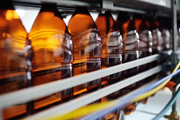 工厂低酒精饮料 苏打水和向日葵用塑料瓶的工业生产油空以棕色pet瓶为背景的现代化设备塑料材料宠物