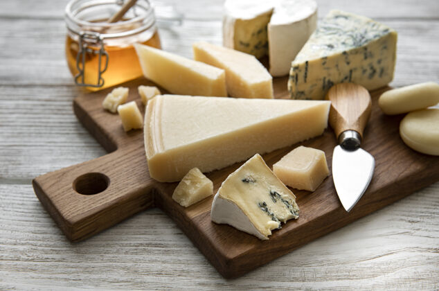 排列白色木桌上摆着各种各样的奶酪饮食什锦健康