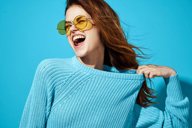 微笑穿蓝色毛衣戴黄色眼镜的情感女人生活方式特写快乐漂亮女性