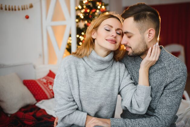 浪漫一对年轻夫妇在圣诞树前拥抱的照片快乐男朋友浪漫