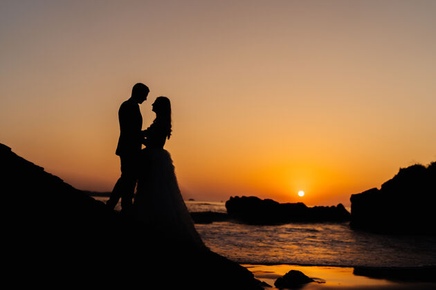约会海滩上夕阳下一对相爱的情侣的剪影热带女人浪漫