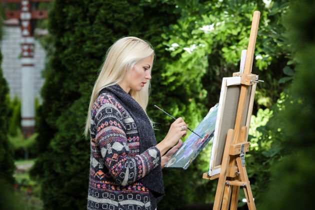 调色板美丽的金发女画家 手里拿着画笔 在大自然的画布上画画艺术品白色成人