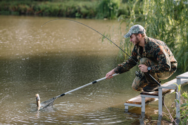 成人一个渔夫拿着鱼竿在河岸上湖泊休闲钓鱼