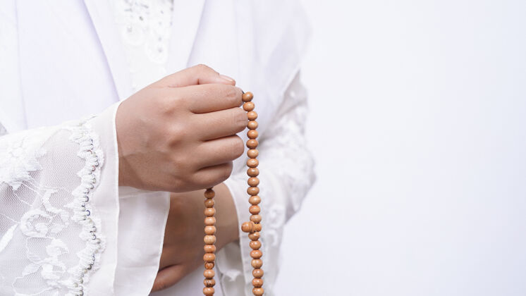 服饰戴着念珠的亚洲妇女与白色塔斯比祈祷上帝手私人