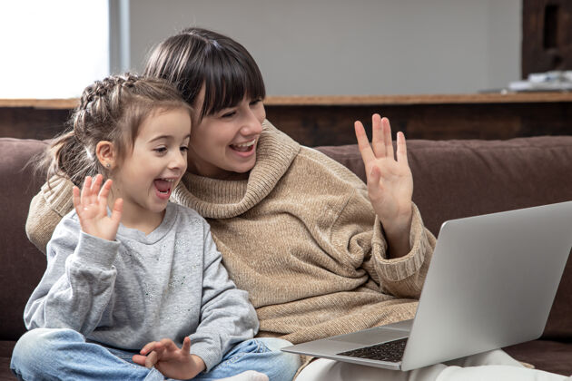 在线幸福家庭看笔记本电脑屏幕做远程视频打电话微笑妈妈和小女孩在网上聊天女儿优质时间通话