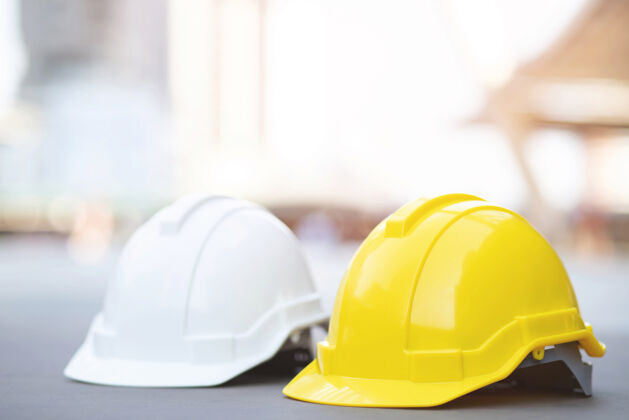 工厂黄色和白色的安全帽 在工程施工现场的混凝土地面上的建筑物阳光.头盔作为工程师或工人概念安全第一工具工程师工业
