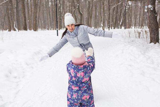 成人家庭 孩子和自然的概念-母亲和女儿在冬季公园玩得开心爱欢呼妈妈
