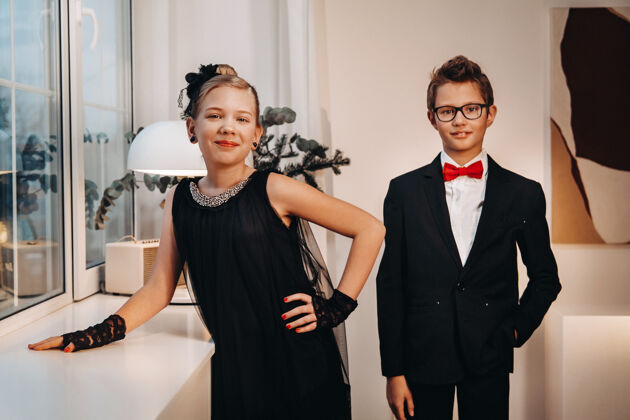 白衬衫时尚优雅的男孩和女孩站在室内的窗户边夹克黑色连衣裙夜晚
