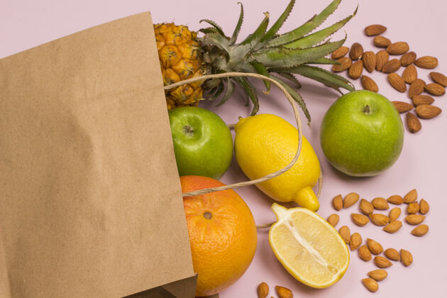 维生素粉红色背景水果纸袋苹果柠檬葡萄柚菠萝坚果健康营养营养素