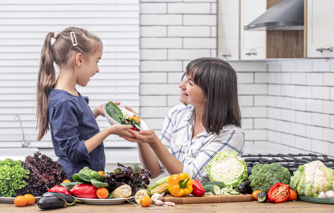 厨房年轻的妈妈带着女儿带着许多蔬菜上了现代厨房的室内空间优质时间健康饮食