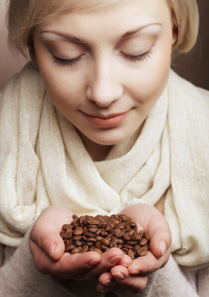 成人金发美女的特写肖像 手里拿着热烘烘的咖啡豆女人味道美女