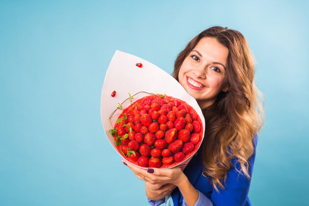 植物拿着一束草莓的年轻女人水果食品草莓