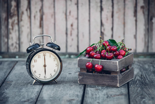 食物夏天 红樱桃和一个旧木桌上的闹钟健身年份开花