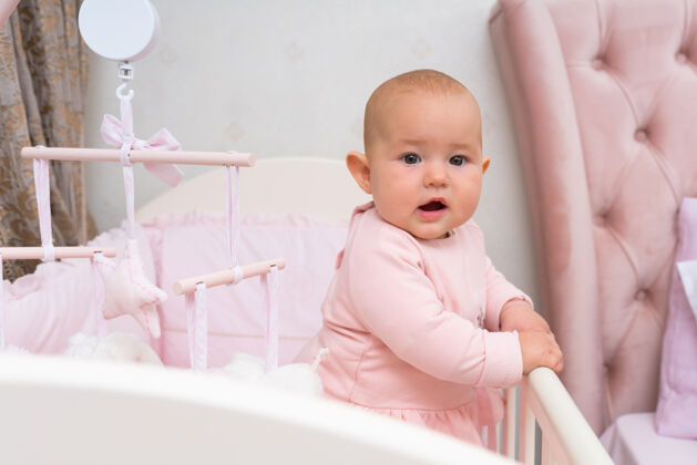 婴儿婴儿床和粉色卧室里挂着手机的场景育儿室内人