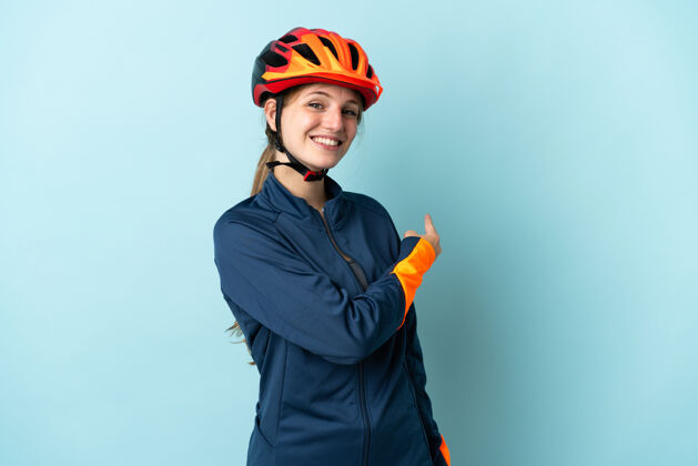 成人一个年轻的骑自行车的女人被隔离在蓝色的背景上指着后面骑自行车自行车年轻