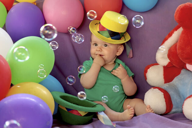 坐一个小孩坐在一个有趣的节日气氛与气球和看肥皂泡配件搞笑玩具