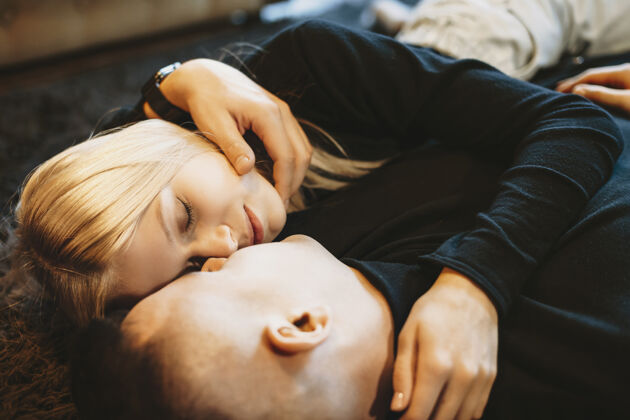 女性俯视图：一对年轻的高加索夫妇倚在家里的地板上 亲吻前微笑着拥抱情侣爱微笑