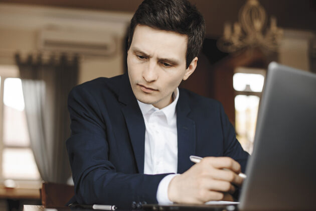 办公桌一位年轻帅气的设计师坐在咖啡馆里工作的特写照片电脑职业笔记本电脑