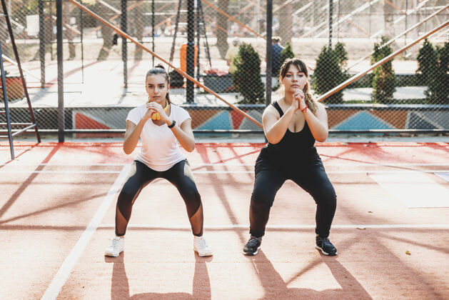 音乐一个身体健康的女人早上和她的女朋友在体育公园里锻炼身体背部公园运动