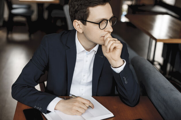 男性一个自信严肃的经理戴着眼镜 一只手放在嘴唇上 一只手放在笔记本上 严肃地看着笔记本电脑屏幕的特写镜头微笑应用程序使用