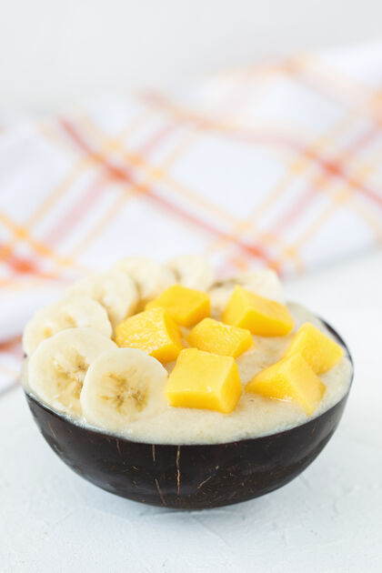 素食主义者黄色素食者自制香蕉和芒果奶制品免费冰淇淋在椰子碗新鲜芒果和香蕉片新鲜奶油鞭子