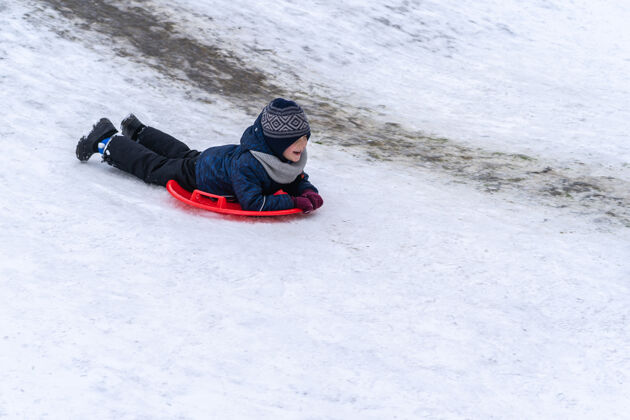 活动一个小男孩在冬天骑雪橇幻灯片.winter假期冰冻一月雪