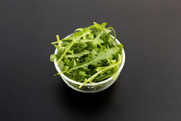 叶子新鲜的绿色火箭色拉放在深色的玻璃碗里饮食吃芦笋