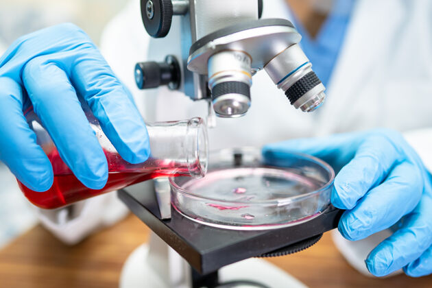 化学亚洲科学家生物化学家或微生物学家在实验室用显微镜进行研究实验工作实验室