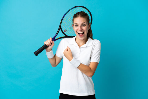成功年轻女子网球运动员在蓝色背景上庆祝胜利年轻私人教练年轻