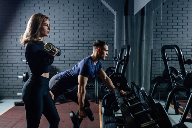 教练情侣们在健身房以哑铃举重为运动 男女一起训练健美健身工作