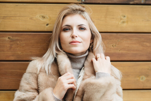 奢华豪华的金发碧眼长发女人 穿着30岁的皮大衣 站在木墙上皮草毛衣风格