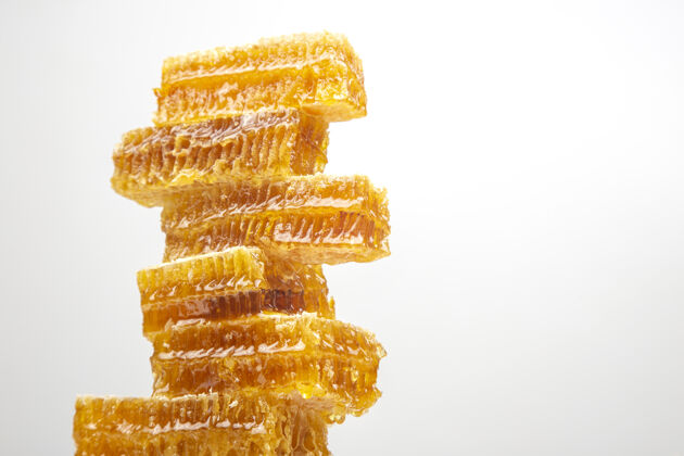 甜点部分新鲜蜂巢上的白色背景.维生素天然的食物.蜜蜂工作成果养蜂吃蜂窝