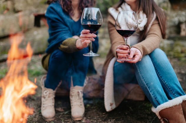 快乐在篝火旁 背景上是一杯红酒 背景上是无法辨认的女人女人有机饮料