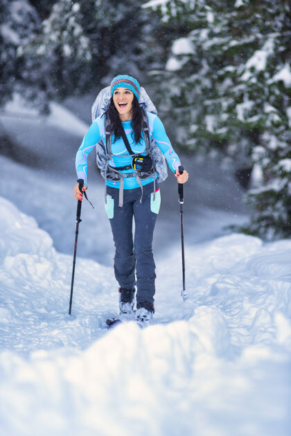 滑雪者美丽的年轻女孩在树林里练习滑雪运动冬天背包