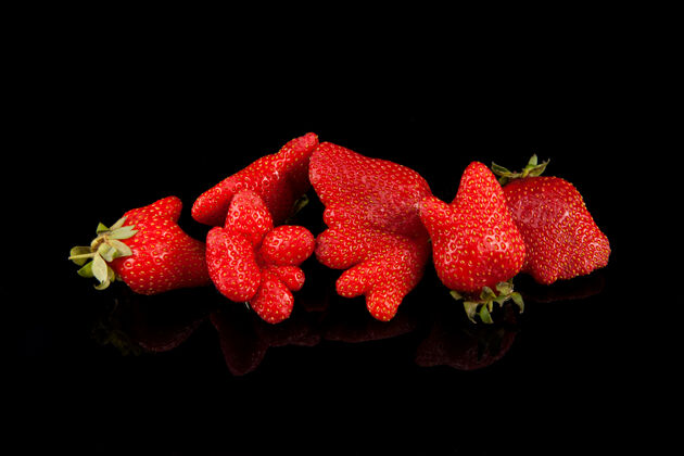 饮食丑陋的有机自家种植的黑色背景与复制草莓空间时尚丑陋的食物奇怪有趣的水果 接近-向上畸形生产 食物垃圾概念美味甜点吃