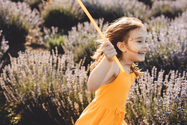 法国美丽的小女孩穿着黄色的衣服在夕阳下的花丛中奔跑冷静微笑女人